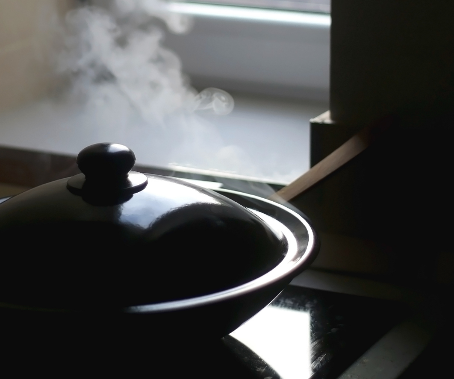 A wok with a lid and some steam escaping