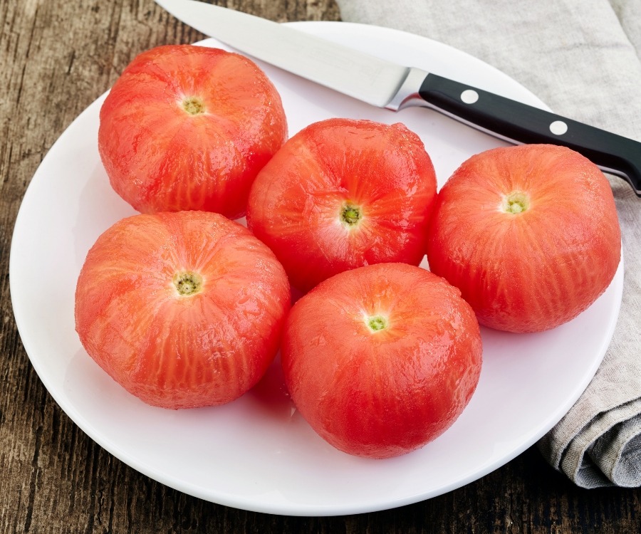 Peeled tomatoes sitting with a knife