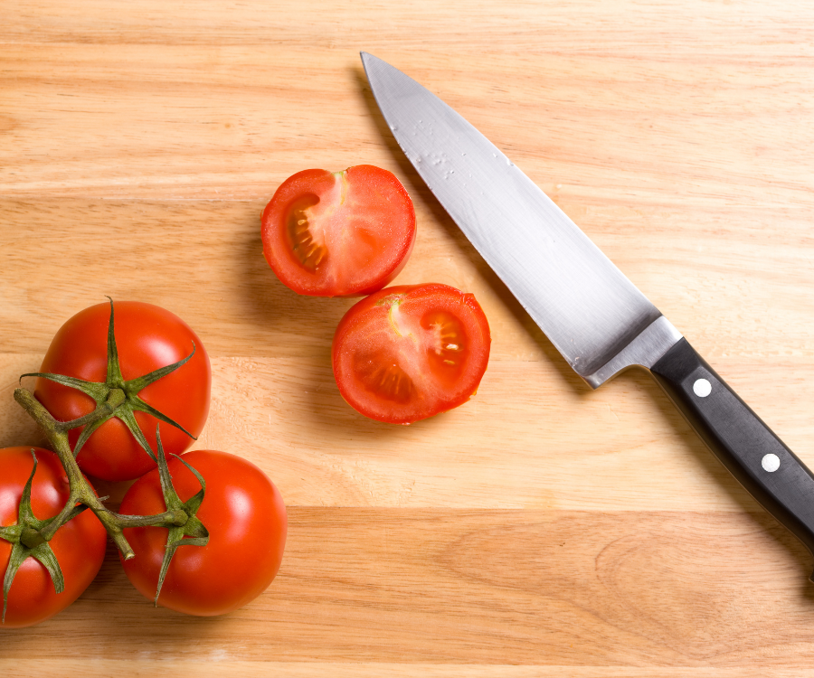 A knive along side tomatoes to show halved tomatoes through their core
