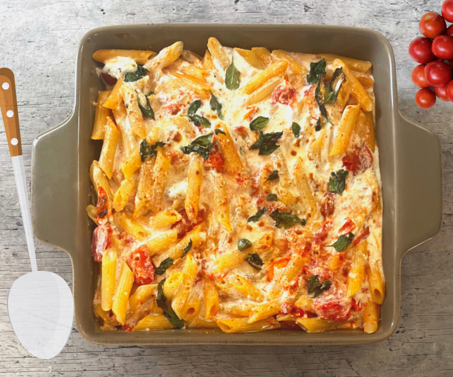 Cherry Tomato Pasta Bake fully grilled and ready to serve, in an over dish with a serving spoon at the side.